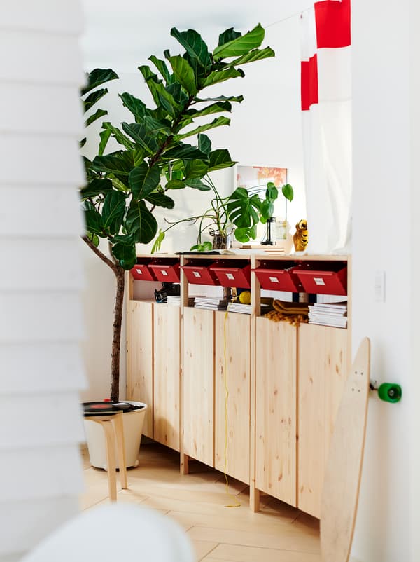 Une rangée d’armoires IVAR sert aussi de séparateur dans une pièce blanche, avec un mix de rangements ouverts et fermés.