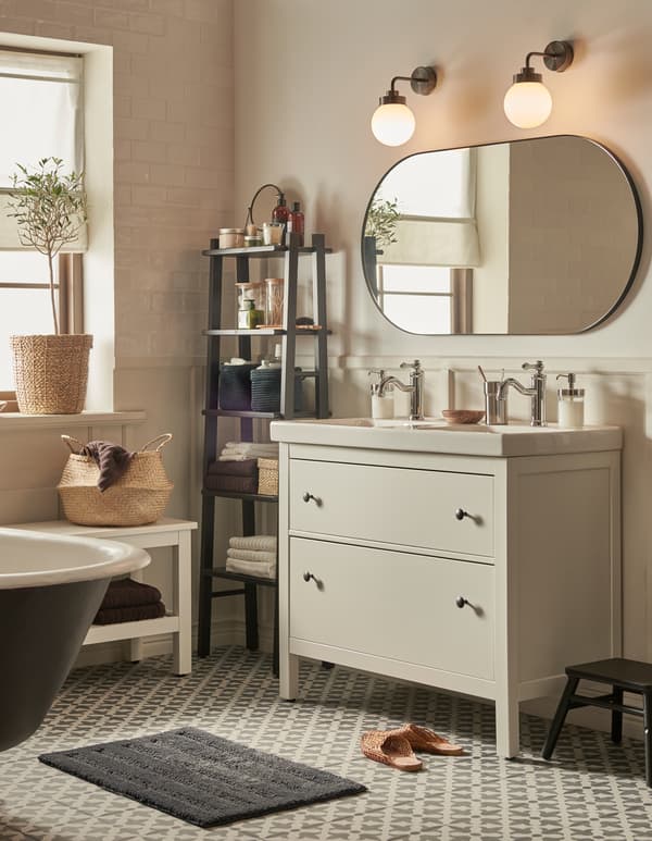 Une salle de bain avec un carrelage style marocain et des couleurs neutres, un meuble lavabo HEMNES avec deux tiroirs, et un grand miroir.