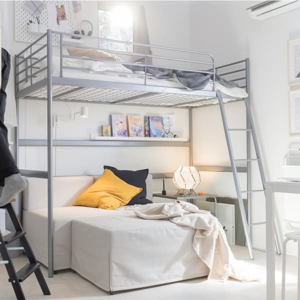 Une structure de lit argentée IKEA SVÄRTA avec un canapé en dessous.