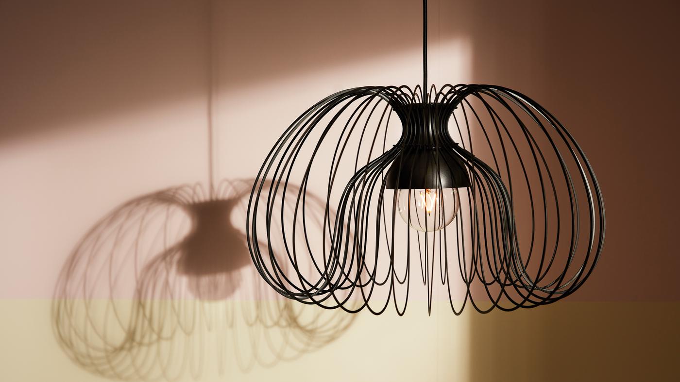 Une suspension métallique KALLFRONT descend du plafond, créant une ombre spectaculaire en arrière-plan.
