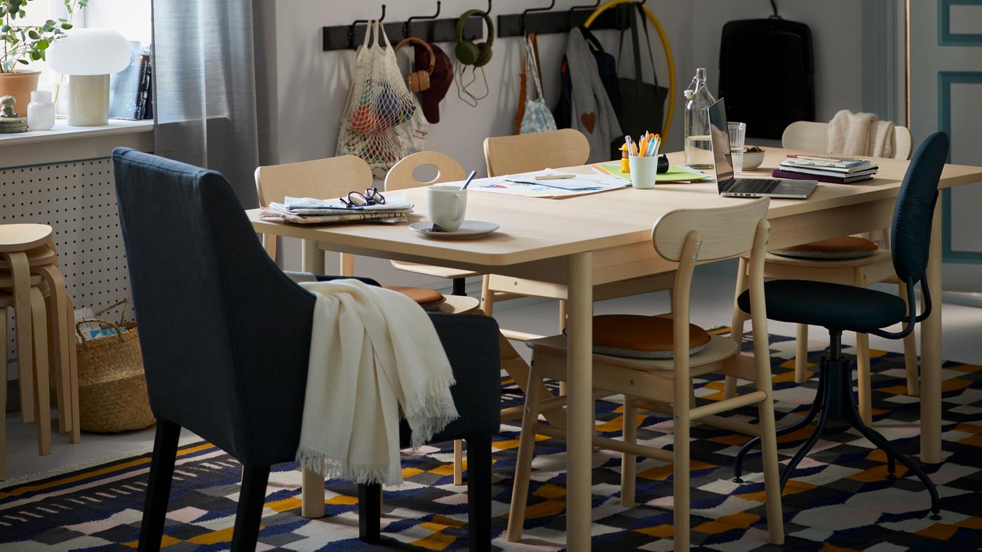 Une zone salle à manger avec une table RÖNNINGE en bouleau avec plusieurs affaires dessus, et des chaises RÖNNINGE sur un tapis TÅRBÄK.