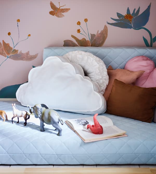 Un'intima zona gioco per bambini realizzata con dei cuscini e un materassino per letto allungabile - IKEA.