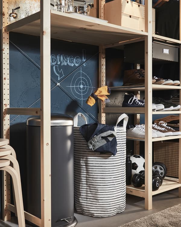 Unit rak kayu yang mempunyai tong dan beg kain kotor dalam ruang kosong yang besar, sasaran rerambut silang dilukis di atas beg kain kotor.