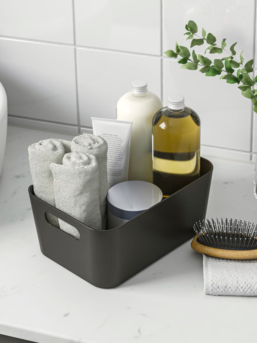 UPPDATERA storage box on a bathroom countertop with several toiletries stored inside.