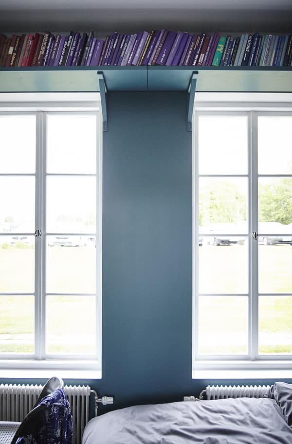Use the dead space above your windows for storing books on a shelf.