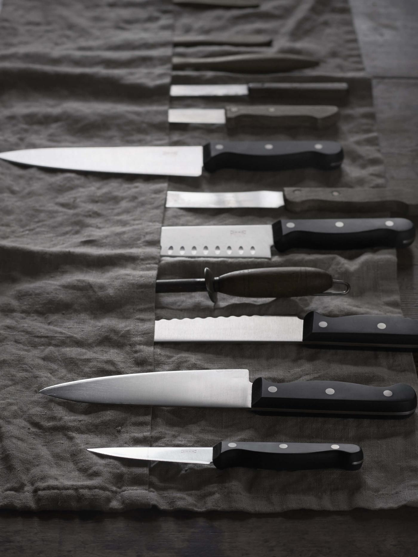 Various knives laying on a dark cloth