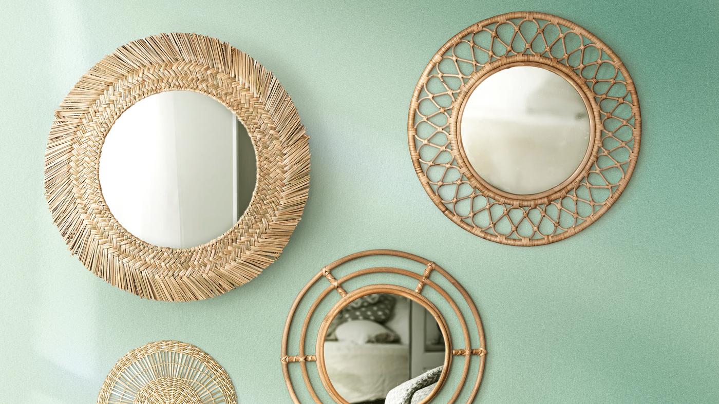 Various sizes of round mirrors with rattan frames are hung on a dark wooden surface to form a focal point.