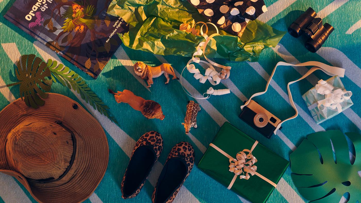 Various wrapped and unboxed gifts and toys along the theme of exploration and adventure lying on a GRACIÖS rug.