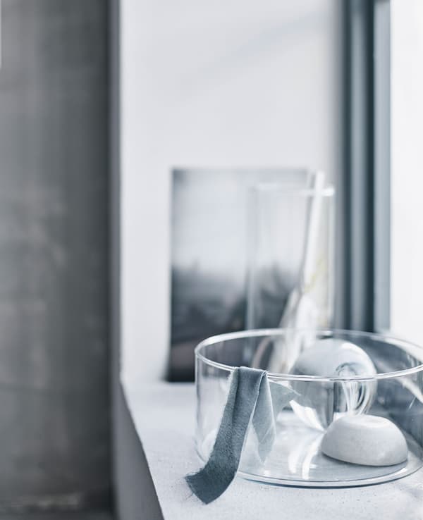 Vase en verre sur un appui de fenêtre baigné de lumière.