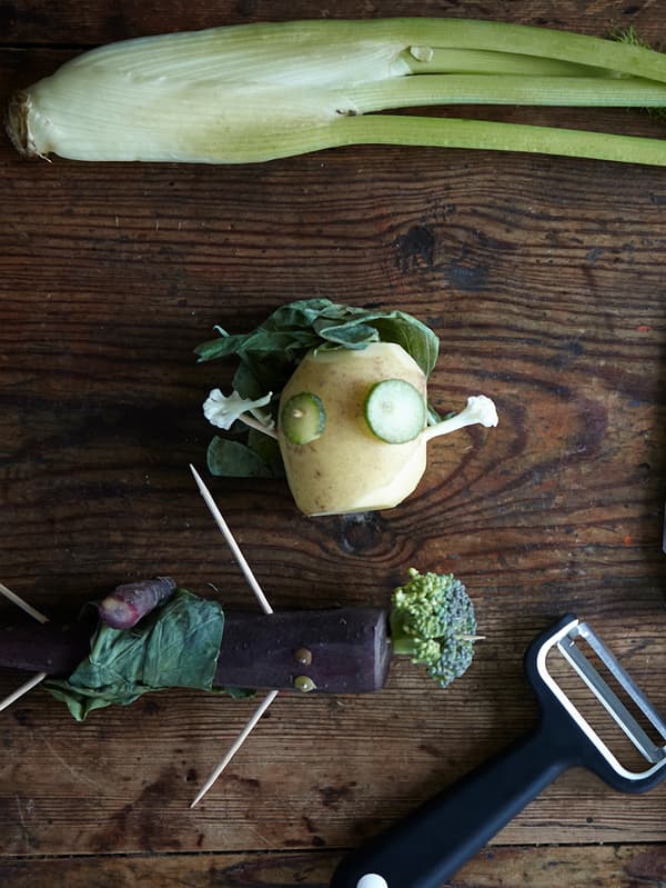 Vegetables cut into the shape of little men and stuck together using toothpicks on a wooden table top with a SMÅBIT peeler.