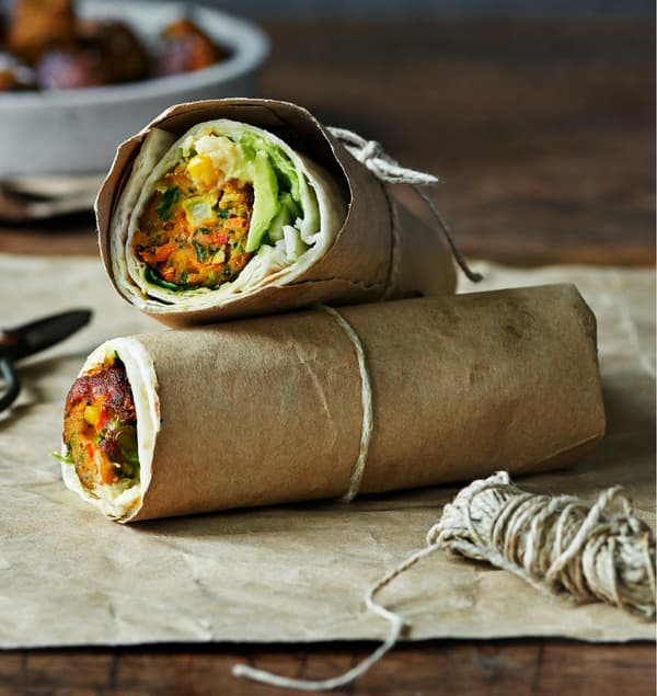 Veggie ball wrap with avocado served in parchment paper held together with a string.