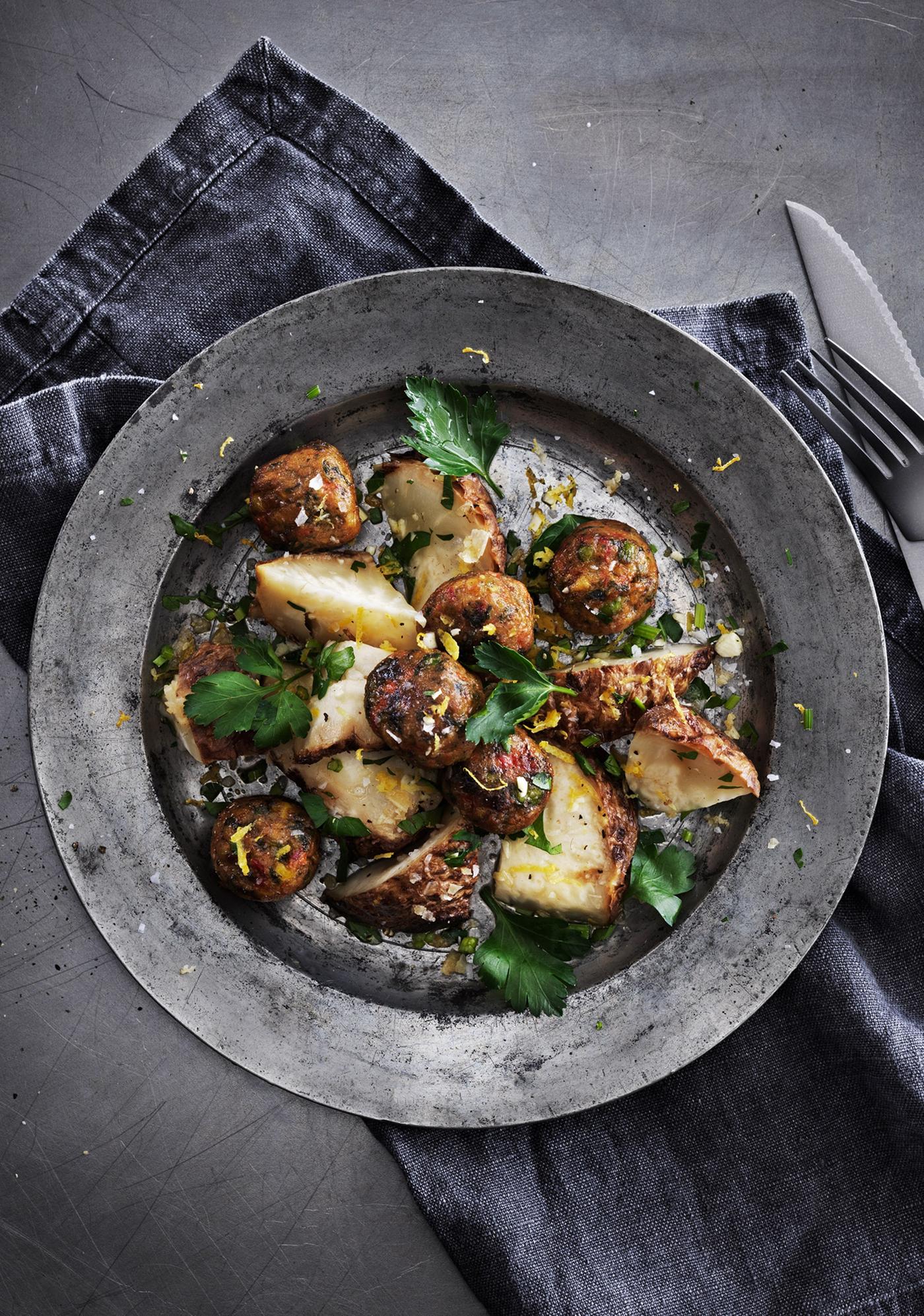 Veggie balls with baked celery root and gremolata served on a plate, seen from above.