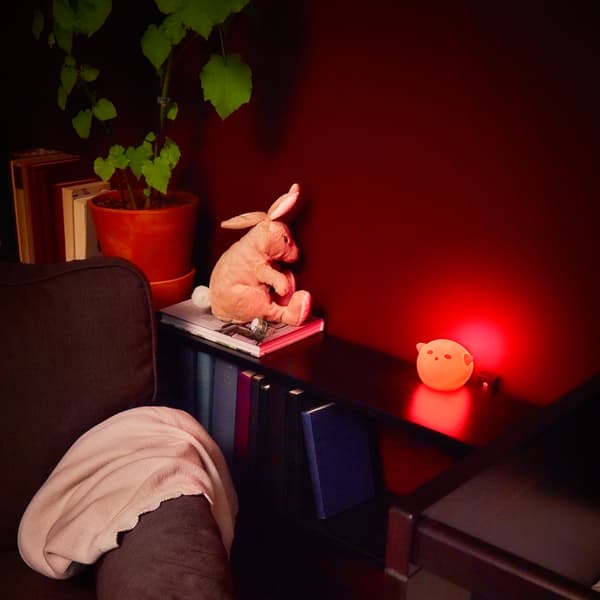 Veilleuse rouge et peluche à côté d'un fauteuil.