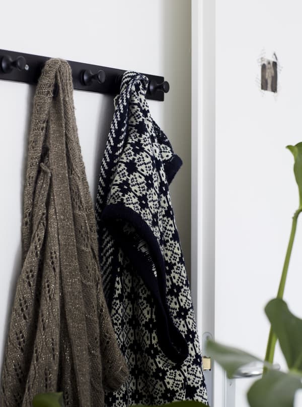 Vêtements accrochés à une patère dans une pièce blanche.