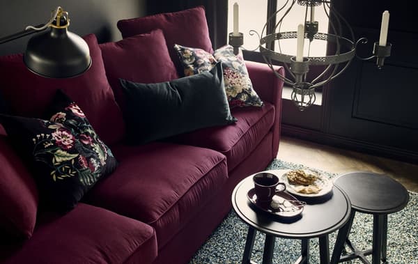 View from above of a living room with a burgundy HÄRLANDA sofa adorned with dark solid and floral velvet cushions 