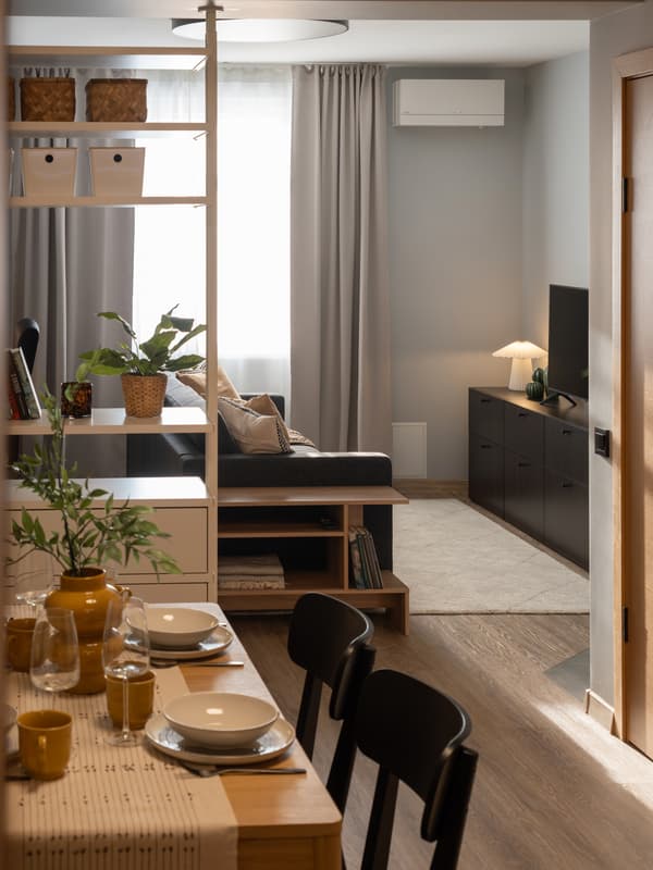 View from the dining area toward the living room, showing a gray sofa behind a white shelving unit. 