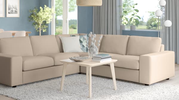 VIMLE modular sofa in beige with L-shaped layout, placed in a bright living room with light blue curtains and white coffee table.