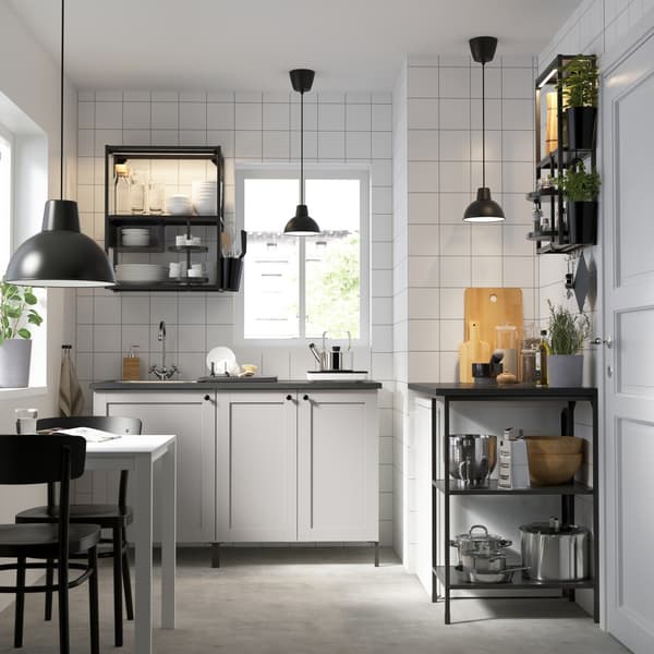 Vista de una cocina con muebles de la serie ENHET de IKEA. Predomina la combinación de muebles blancos y negros de madera.
