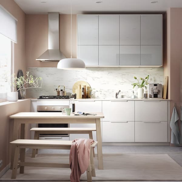 Vista de una cocina con muebles de la serie METOD: Una mesa con dos banquetas, una lámpara de cocina blanca.