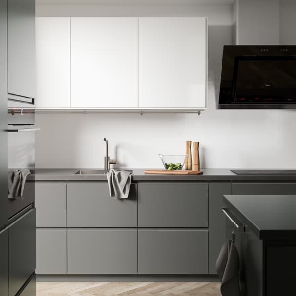 Vista frontal de una cocina con muebles METOD sin tiradores, de colores blanco y gris. El diseño de la cocina es minimalista y el piso tiene un diseño de tablones de madera. 
