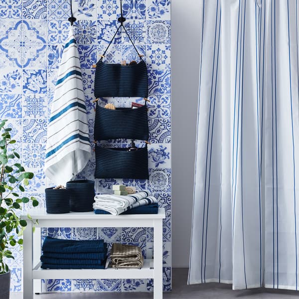 Vive le bleu ! Carreaux de salles de bains, rideau de douche rayé, rangement suspendu et serviettes.