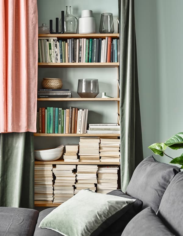 Vous souhaitez retrouver l’équilibre dans le salon, alors dissimulez une bibliothèque derrière des rideaux. IKEA propose un grand choix de rideaux et de textiles pour la maison. Ici, les rideaux roses LEJONGAP en matières naturelles ont un look irrégulier, brut.