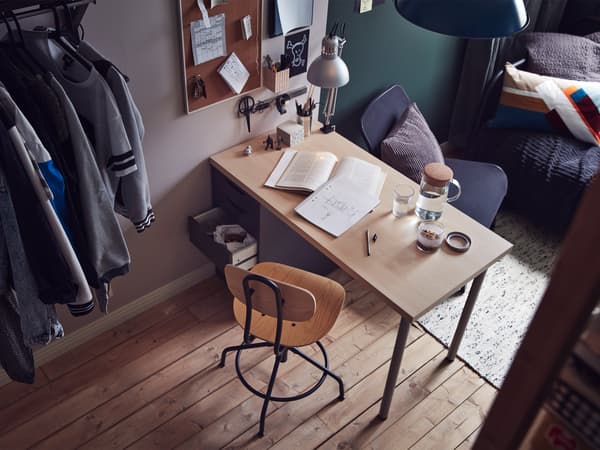 Vue de la chambre prise d’un coin, avec bureau et chaise à l’avant-plan et divan à l’arrière-plan.