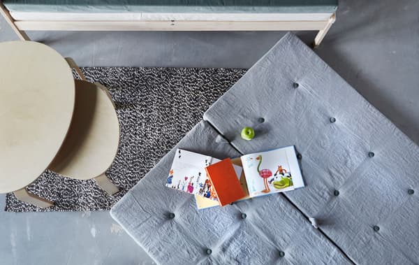  Vue d’ensemble d’un matelas posé sur le sol, à côté de tables basses et d’un canapé