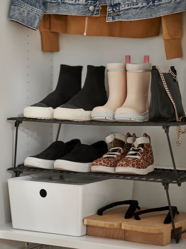Vue partielle d’une garde-robe dotée d’une étagère à chaussures GREJIG parmi d’autres vêtements et accessoires.