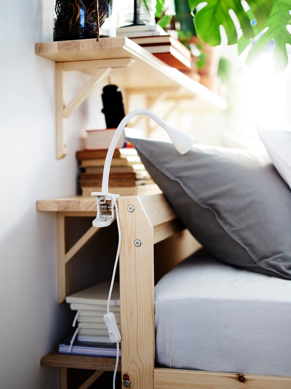 Wall shelves fill the space between a wall and the head end of a bed, creating a combination of storage and bedside table.