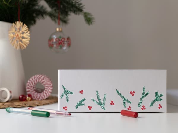 Weihnachtliche Motive werden auf den Rand der TJENA Schachtel gemalt.