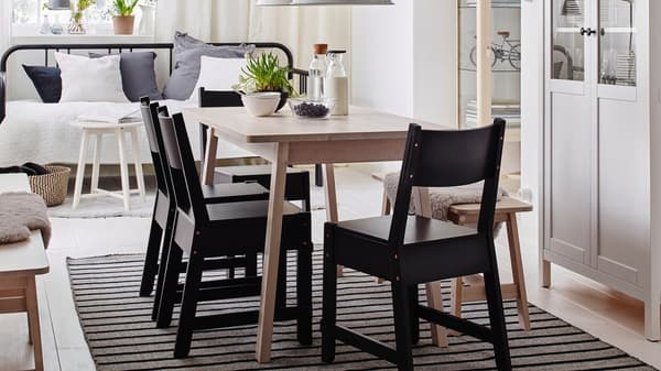 Weißer NORDEN Tisch mit schwarzen Stühlen im skandinavischen Stil