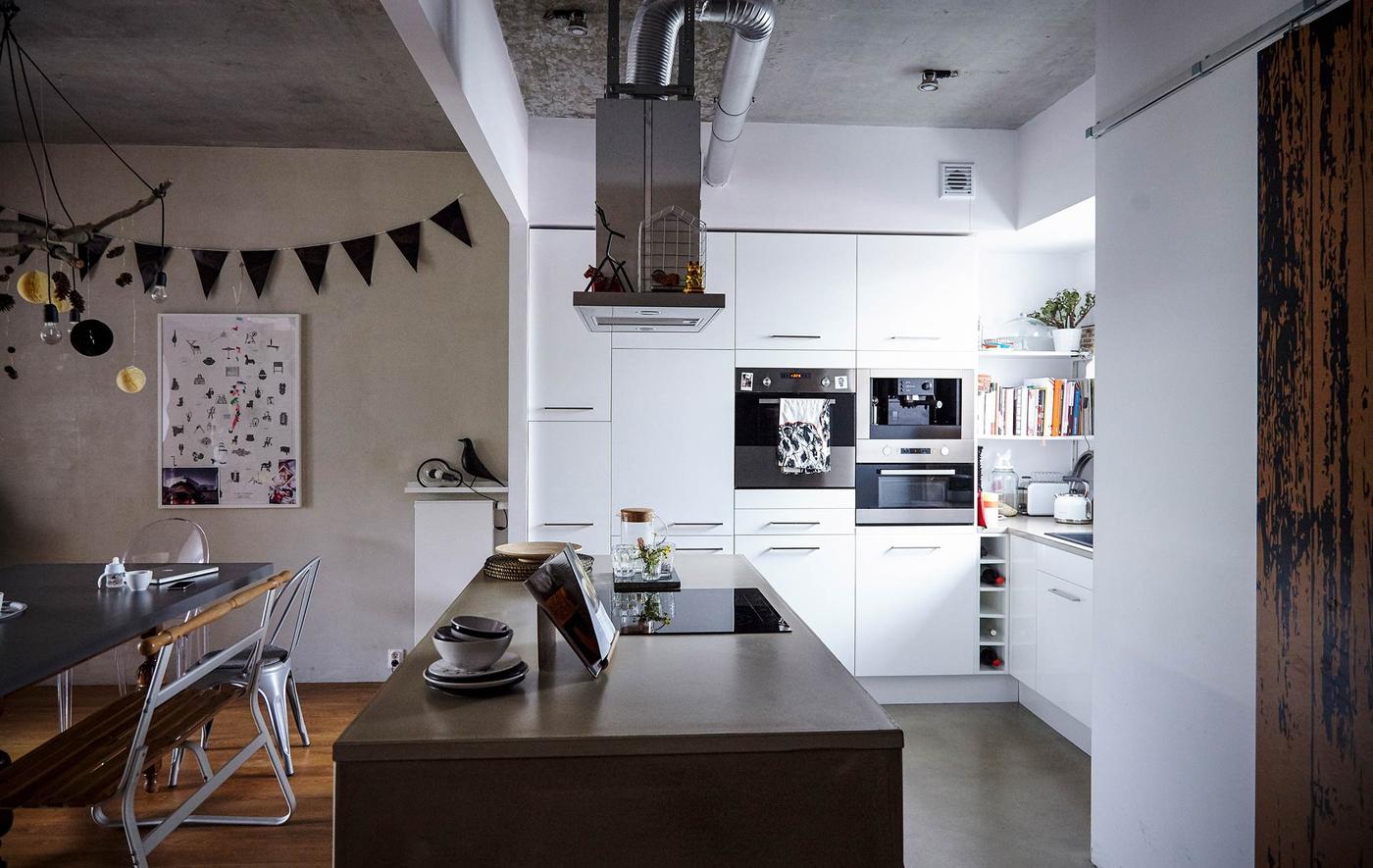 White cabinets and a large kitchen island with concrete counter top in a white, modern kitchen.