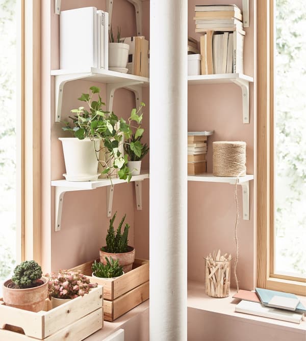 White EKBY ÖSTEN shelves and EKBY STÖDIS brackets create corner storage in a pink living room.