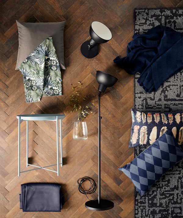 White GLADOM tray table laying on a wooden floor amongst a collage of lamps and cushions.