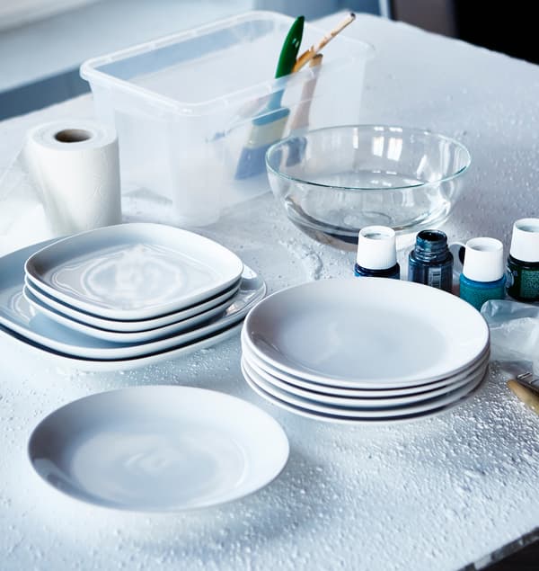 White IKEA FÄRGRIK plates are stacked on a table, ready to be painted.