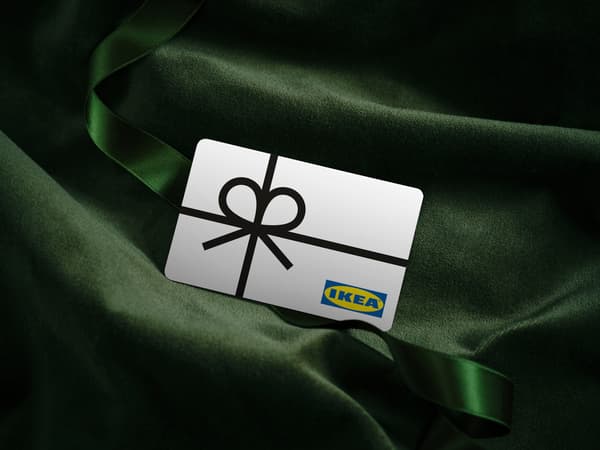 White IKEA gift card with a picture of a black ribbon on a background of green velvet fabric.