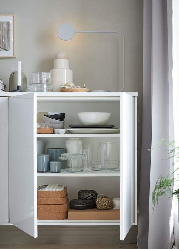 White IKEA METOD wall cabinets, with white doors in a glossy finish, used to store tableware on the shelves.