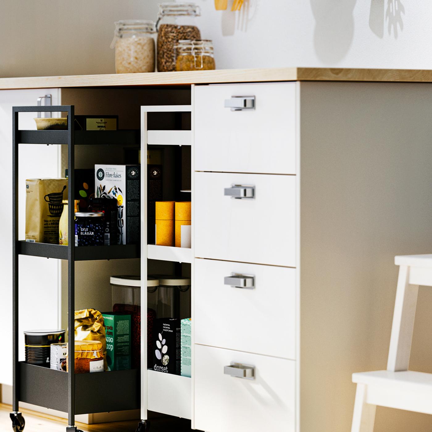 White METOD base cabinets and an EKBACKEN worktop with NISSAFORS trolleys, one black and one white, in a recess below.