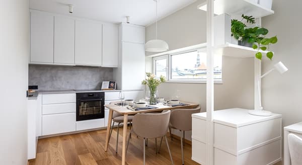 White modern kitchen with dining table and built-in cabinets.