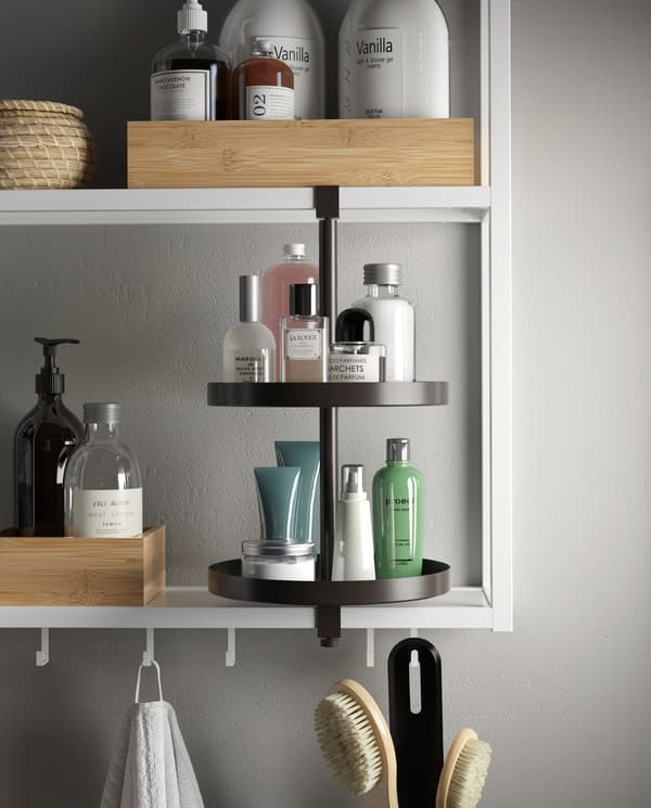 White shelving unit with hooks and a black swivel shelf. Trays, boxes, perfumes, lotions and more are on the shelves.