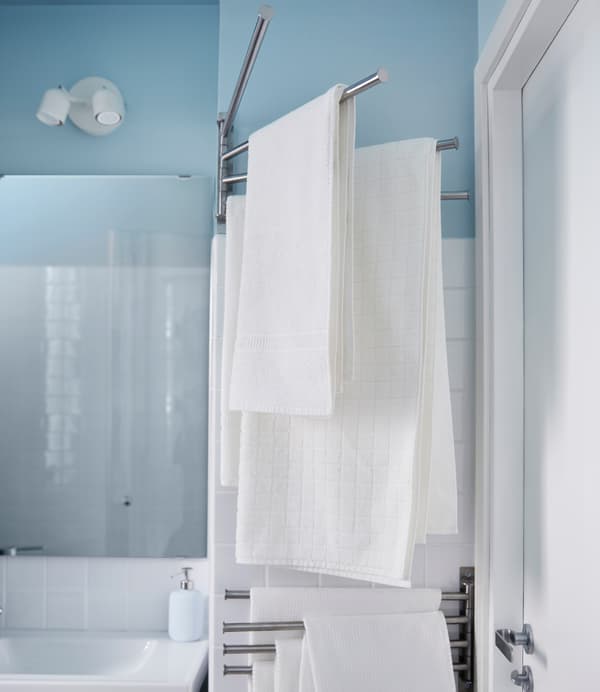 White towels hang on a towel rack that swings in and out from the wall in this small bathroom.
