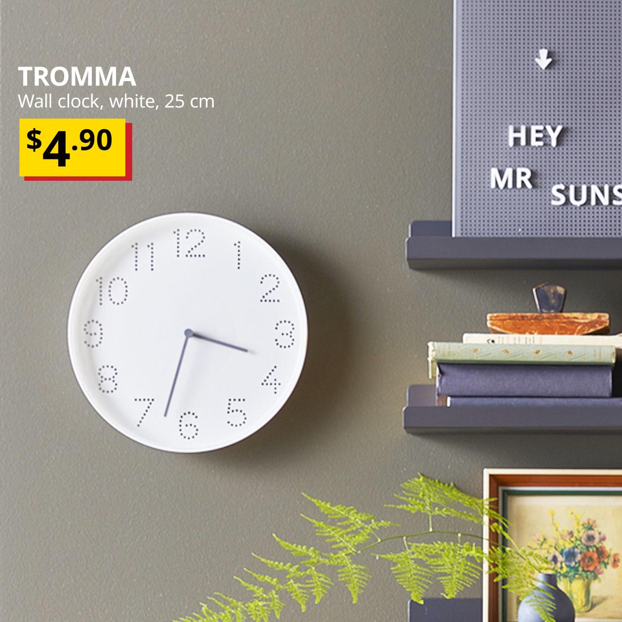 White TROMMA wall clock hanging on a dark green wall. Price: $4.90.