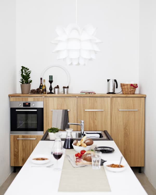 Wit keukeneiland met ingebouwde spoelbak in een kleine keuken met houten kasten