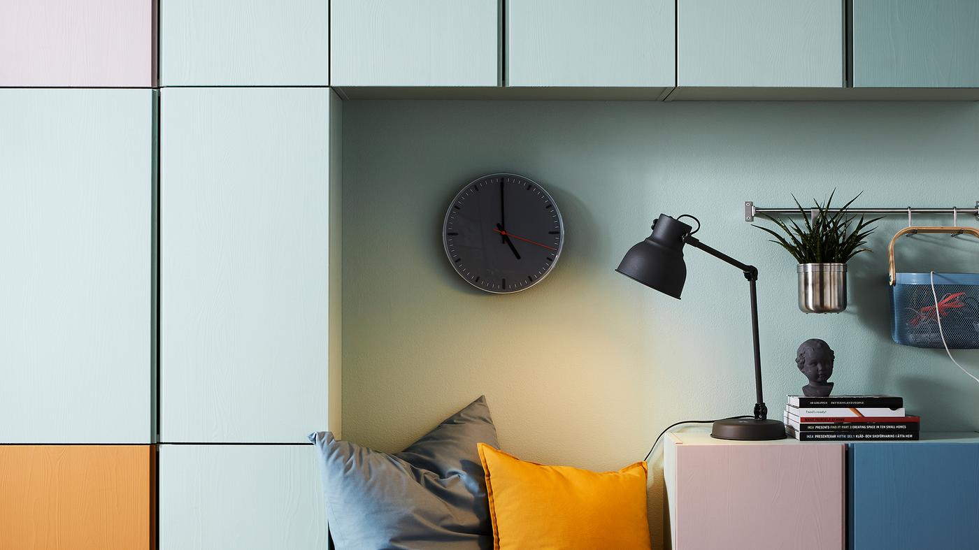 Wohnzimmeraufbewahrung mit farblich aufgeteiltem IVAR Aufbewahrungselement an einer Wand, u. a. in Orange, Weiß, Blau und Rosa.