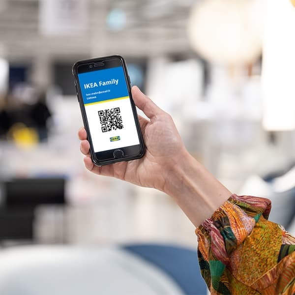Woman holding a phone with IKEA Family card in it
