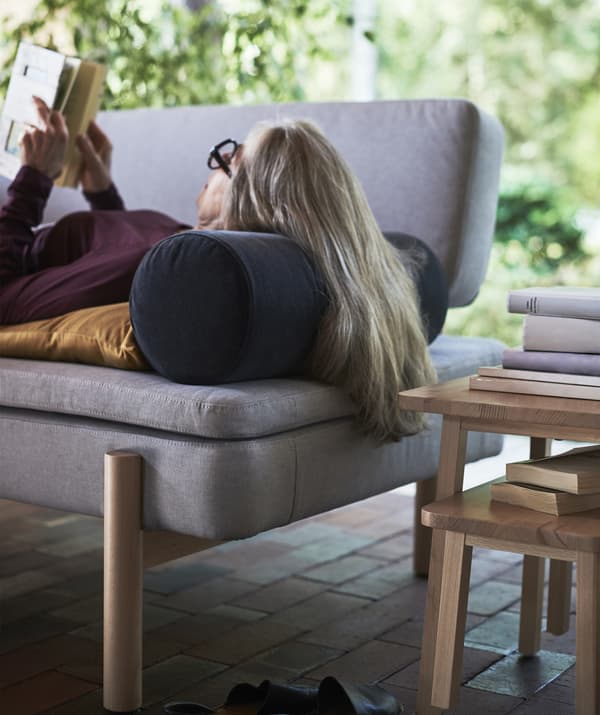 Woman lying on a sofa with her head on an armrest cushion.