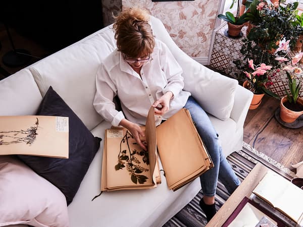 Woman reading and sitting on a FÄRLÖV white sofa.
