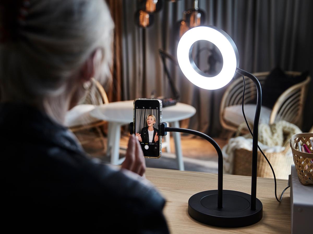 Woman recording herself on her phone in front of a ring light.