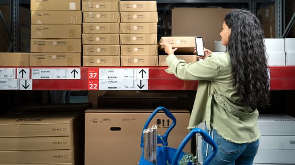 Woman scans the barcode of a flat pack of an IKEA product.